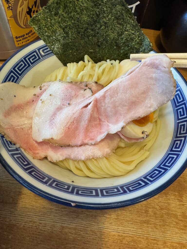 「極太麺をスープにくぐらせた一口|魚介と辛味が絡む濃厚な味わい」