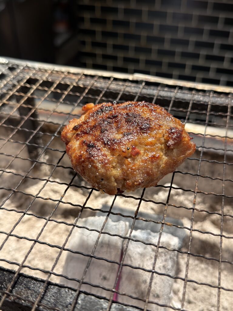 都ハンバーグの炭火焼き地鶏ハンバーグ。客席前の網に置かれ、表面に香ばしい焼き目が付いた焼きたての一品