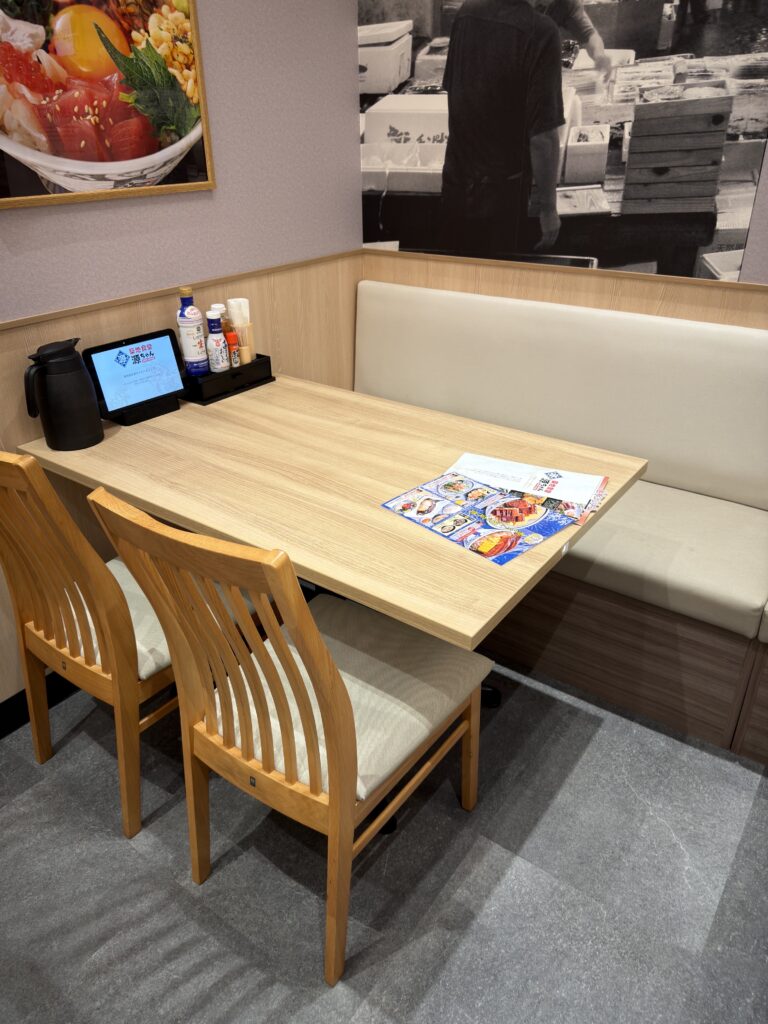 築地食堂源ちゃんゆめタウン佐賀店のテーブル席。ソファー席と木製の椅子があり、家族でゆっくり食事をしやすい清潔感のある店内