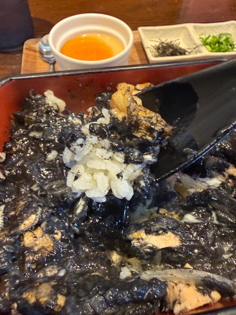 すみまるの黒い親子丼を卵黄と混ぜた様子。炭火焼の鶏と黒いタレがご飯に絡み、炭火の香りを楽しめる親子丼